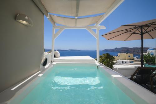 a swimming pool on the side of a house with an umbrella at Sophia Oia View in Oia