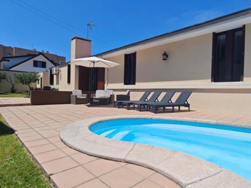 a swimming pool with two chairs and a house at Casa na praia - com piscina in Esmoriz