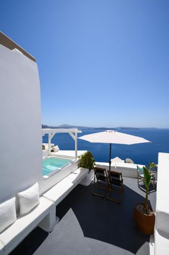a balcony with a swimming pool and an umbrella at Sophia Oia View in Oia