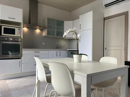 une cuisine blanche avec une table et des chaises blanches dans l'établissement Appartement avec cour à côté de la plage, à Palavas-les-Flots