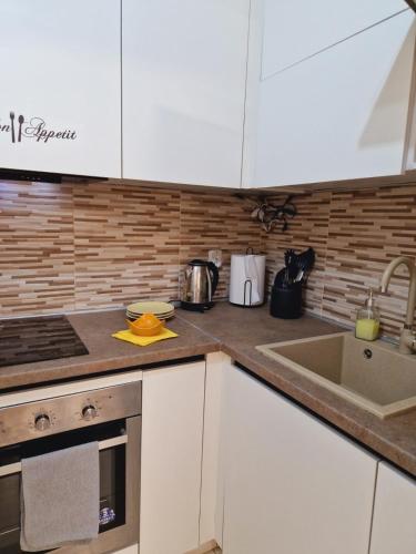 eine Küche mit weißen Schränken und einer Spüle in der Unterkunft Kamche apartment in Skopje