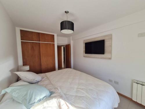 a bedroom with a bed with a tv on the wall at AC suites, vista al mar ! in Puerto Madryn
