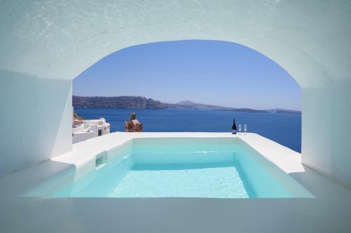 a swimming pool in a white building with the ocean in the background at Sophia Oia View in Oia