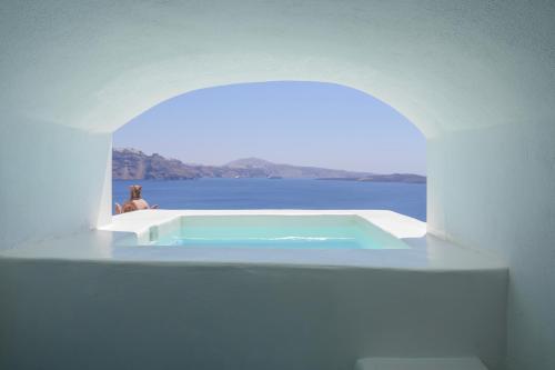 a person sitting in a bath tub in a white building at Sophia Oia View in Oia