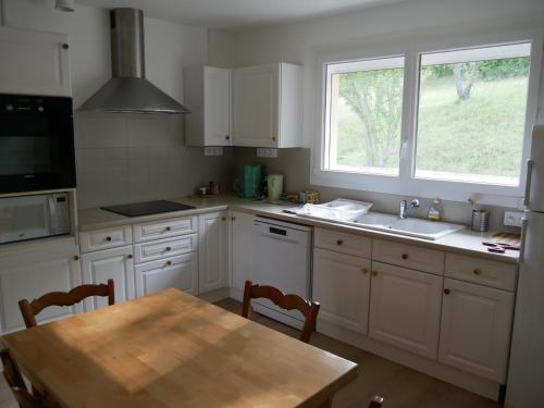 une cuisine avec des armoires blanches, une table et une fenêtre dans l'établissement Villa Horizon, à Châtel-Guyon