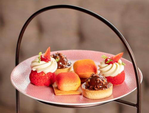 a pink plate with strawberries and desserts on it at SCHLOSS Roxburghe, part of Destination by Hyatt in Kelso