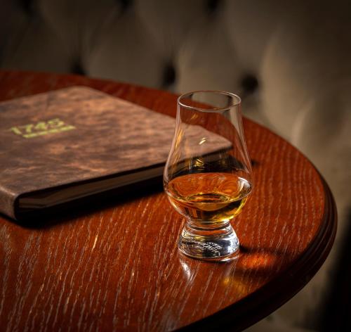 a glass of whisky sitting on a table next to a book at SCHLOSS Roxburghe, part of Destination by Hyatt in Kelso