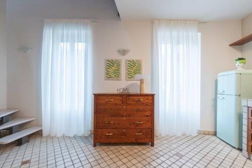 a dresser in a kitchen with white curtains and a refrigerator at Loft Gelsomino, by R Collection apartment in Cernobbio