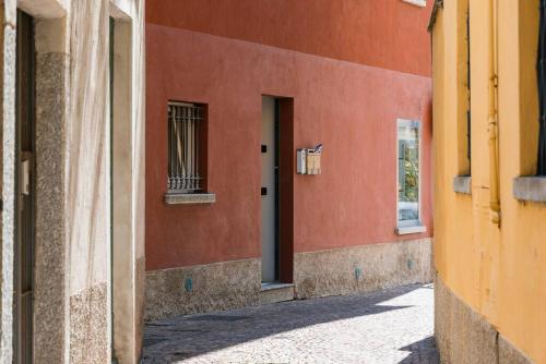 an alley with a red building with a window at Loft Gelsomino, by R Collection apartment in Cernobbio