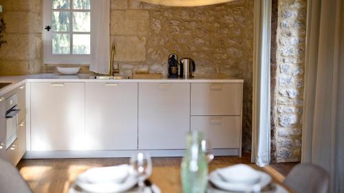 - une cuisine avec des placards blancs et une table avec de la vaisselle dans l'établissement Village des Éléments, à Naussannes