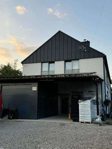 a white and black building with a garage at Szarów 414 in Szarów