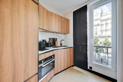 une cuisine avec des placards en bois et une grande fenêtre dans l'établissement Charming apt - 2BR-4P - Arc de Triomphe, à Paris