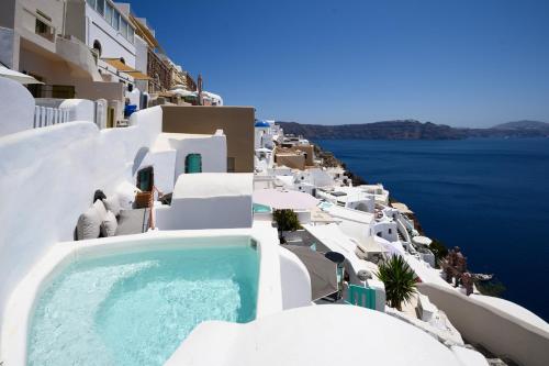 a swimming pool on the side of a building next to the water at Sophia Oia View in Oia