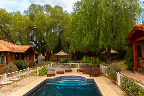 La Cuyanita - Complejo de cabañas في ميرلو: حديقة خلفية بها مسبح وكراسي وأشجار