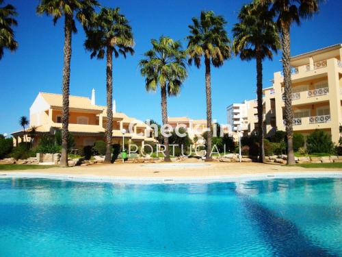 a swimming pool with palm trees in front of a building at Ellegance - Shared Pool - 6 Guests - Vilamoura in Vilamoura