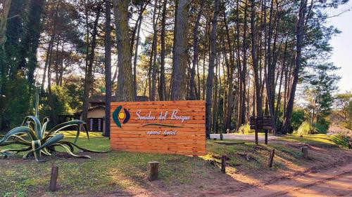 a wooden sign in a park with trees in the background at Sonidos Del Bosque in Mar de las Pampas
