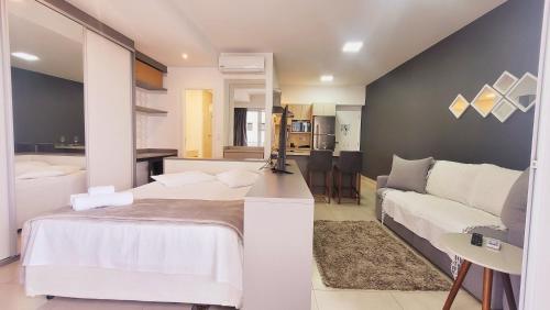 a bedroom with a white bed and a couch at Book Santos - Unlimited 618 - Veja e escute o Mar in Santos