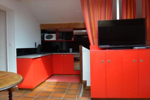 Il comprend une cuisine avec des placards rouges et une télévision à écran plat. dans l'établissement Coquet et spacieux Appt 3 chambres dans villa avec terrasse et jardin, à Urrugne
