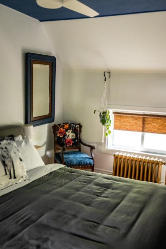 a bedroom with a bed and a chair and a window at Au Loup, maison élégante avec arrivée autonome in Waterloo
