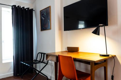 a room with a desk with a television on the wall at Hotel Burrhus in Vaison-la-Romaine
