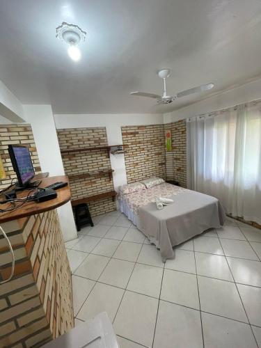 a bedroom with a bed and a desk with a laptop at Pousada Ramo de Acácia in Bombinhas