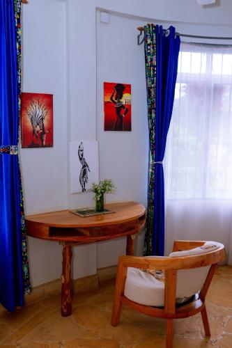 a table and a chair in a room with paintings at Kilimanjaro Scenic Homestay in Moshi