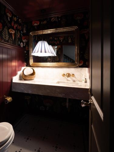 a bathroom with a sink with a mirror and a toilet at The Madison Hotel in Dallas