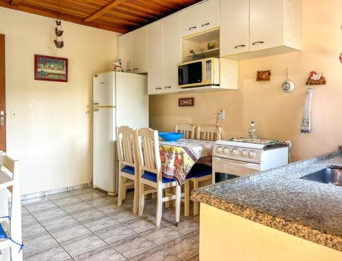 a kitchen with a table and a white refrigerator at Chácara com piscina, churrasqueira, WiFi e quadra in Mairinque