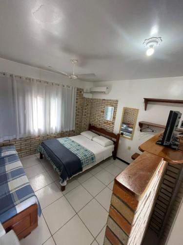 a bedroom with a bed and a television in it at Pousada Ramo de Acácia in Bombinhas