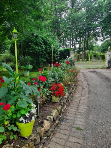 een tuin met rode bloemen en een straatlicht bij Chambre d hôte les bosquets in Caugé