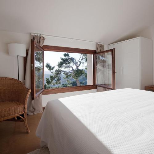 a bedroom with a white bed and a window at La Torreta de Aitana in Confrides