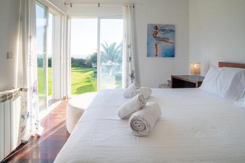 Un dormitorio con una cama blanca con toallas. en Villa Atlantic Blue, en Ericeira
