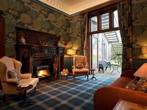 a living room with a fireplace and a couch and chairs at SCHLOSS Roxburghe, part of Destination by Hyatt in Kelso