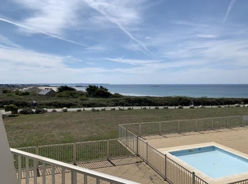 a balcony with a swimming pool and a view of the ocean at Esprit loft face à l'océan in Guidel