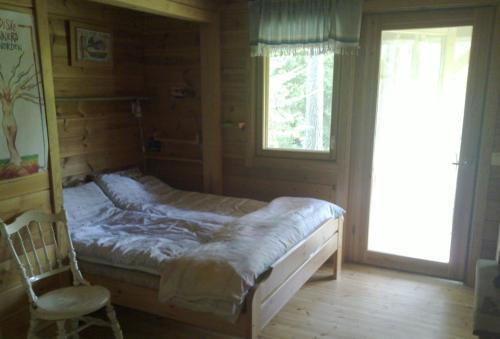 ein Schlafzimmer mit einem Bett, einem Stuhl und einem Fenster in der Unterkunft Soludden in Raseborg