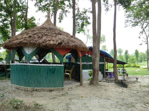 a hut with a straw roof and a table at Sudarshan Resort in Haraincha
