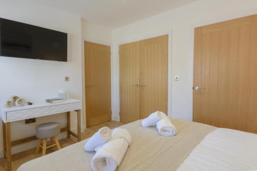 a bedroom with towels on a bed with a desk at The Orchard in Telford