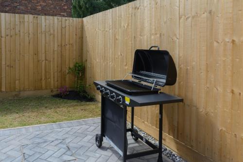 a grill sitting on top of a black table next to a fence at The Orchard in Telford
