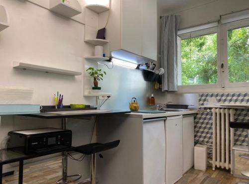 une cuisine avec des armoires blanches, un évier et une fenêtre dans l'établissement Paris Tour Eiffel Mirabeau, à Paris