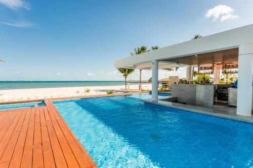 a swimming pool next to a beach with a house at Increíble dpto de lujo con acceso a club de playa in Cancún