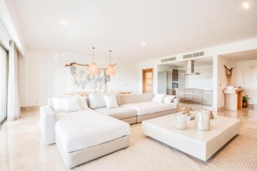 Una sala de estar blanca con sofás y mesas blancos. en Increíble dpto de lujo con acceso a club de playa, en Cancún