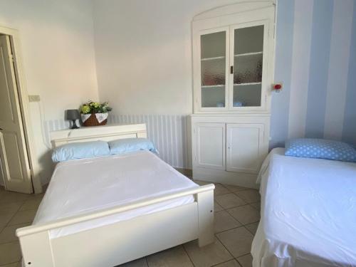 a white bedroom with two beds and a window at Casa Elvira in Imperia