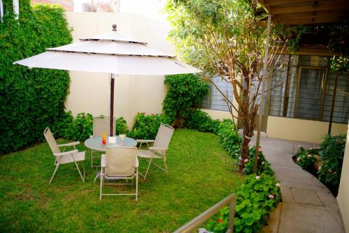 a table and chairs with an umbrella in the grass at Hotel Elizabeth Central in Aguascalientes
