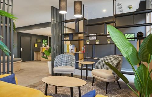a lobby with chairs and tables and plants at Appart Hotel Odalys City Aix en Provence L'Atrium in Aix-en-Provence