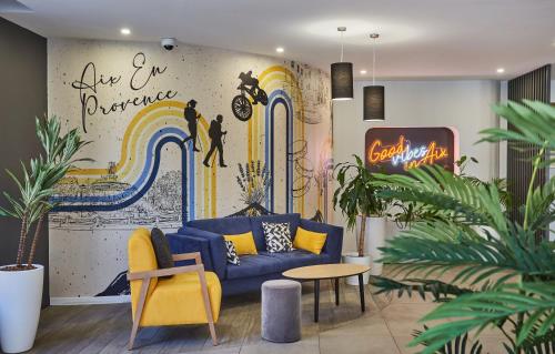a living room with a blue couch and a mural at Appart Hotel Odalys City Aix en Provence L'Atrium in Aix-en-Provence