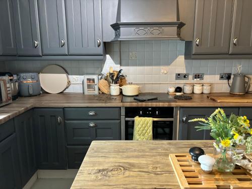 a kitchen with blue cabinets and a wooden counter top at Pemberton cottage in Ingleton 
