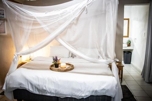 a bedroom with a white canopy bed with candles on it at East Africa Safaris in Chizavane