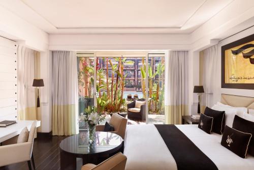 a hotel room with a bed and a table and chairs at H&ocirc;tel & Ryads Barri&egrave;re Le Naoura in Marrakech