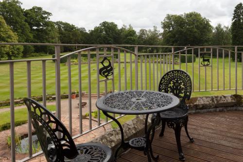 a table and chairs on a deck with a fence at SCHLOSS Roxburghe, part of Destination by Hyatt in Kelso