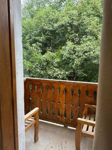 a balcony with a wooden fence and a bench and trees at Verin Tun in Dilijan